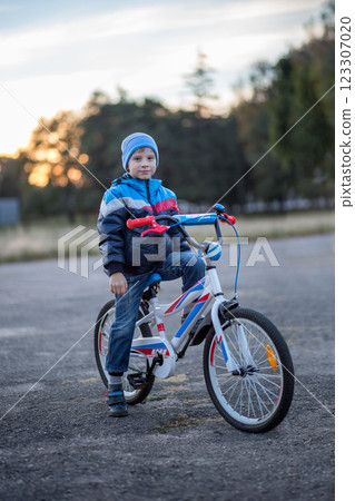 Young boy rides a bicycle during sunset in a rural setting 123307020