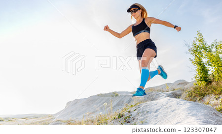 Runner jumps over rocky terrain during sunny outdoor workout in nature Runner jumps over rocky terrain during sunny outdoor workout in nature 123307047