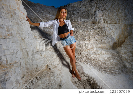Young woman in shirt and shorts posing in a rugged outdoor landscape at dusk Young woman in shirt and shorts posing in a rugged outdoor landscape at dusk 123307059