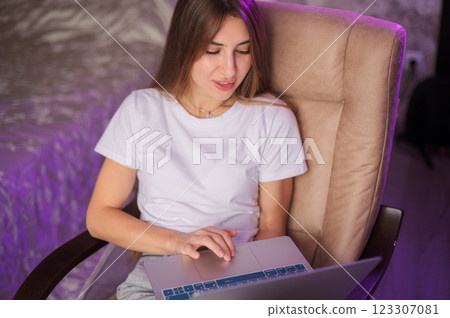 Young woman freelance working comfortably on laptop in modern indoor space during evening hours with warm lighting 123307081