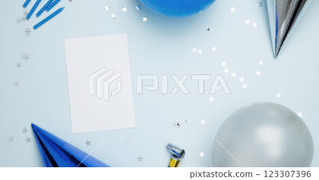 Concept of festive birthday celebrations. Blank card surrounded by colorful balloons, party hats, candles, confetti 123307396