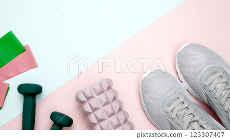 Healthy lifestyle. Fitness accessories including sneakers, dumbbells, resistance bands on pastel backgrounds Healthy lifestyle. Fitness accessories including sneakers, dumbbells, resistance bands on pastel backgrounds 123307407