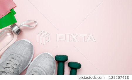 Healthy lifestyle. Fitness accessories including dumbbells, resistance bands on pastel backgrounds Healthy lifestyle. Fitness accessories including dumbbells, resistance bands on pastel backgrounds 123307418