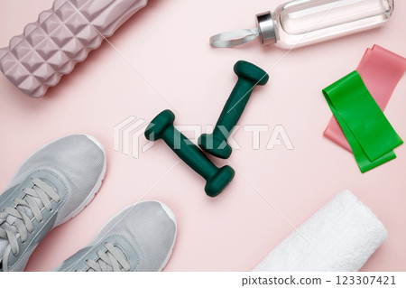 Various accessories for sports and fitness, including sneakers, dumbbells, resistance bands, a foam roller for myofascial release, a water bottle, a towel 123307421