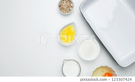 Flat lay composition for cooking preparation.Empty white baking dish with ingredients for baking, including egg, milk, butter, sugar, nuts Flat lay composition for cooking preparation.Empty white baking dish with ingredients for baking, including egg, milk, butter, sugar, nuts 123307424