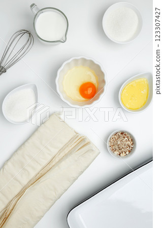 Baking Crinkle Cake. Near baking dish with ingredients, phyllo dough, egg, butter, nuts, milk 123307427