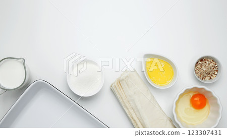 Baking Crinkle Cake. Near baking dish with ingredients, phyllo dough, egg, butter, nuts, and milk 123307431