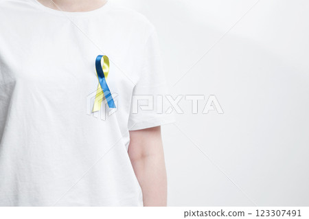 A person wearing a white t-shirt with a yellow and blue awareness ribbon, symbolizing World Down Syndrome Day A person wearing a white t-shirt with a yellow and blue awareness ribbon, symbolizing World Down Syndrome Day 123307491