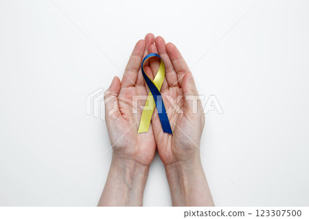 A person holds a yellow and blue awareness ribbon, symbolizing World Down Syndrome Day 123307500