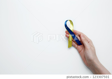 A person holds a yellow and blue awareness ribbon, symbolizing World Down Syndrome Day A person holds a yellow and blue awareness ribbon, symbolizing World Down Syndrome Day 123307501