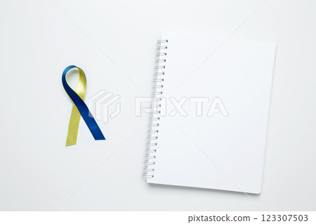 A yellow and blue awareness ribbon, symbolizing World Down Syndrome Day. White notebook mockup 123307503