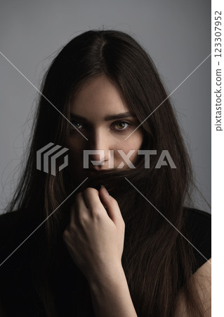 Close-up beautiful woman studio portrait with holding her hairs with hand 123307952