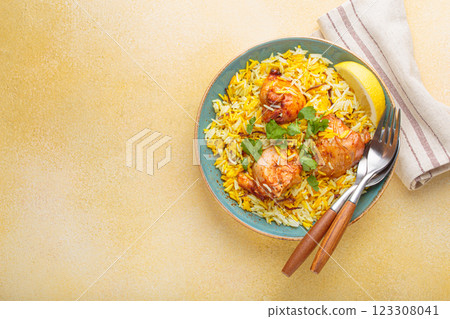 Traditional Indian dish chicken biryani with cilantro and lemon in a bowl top view on beige background with space for text 123308041