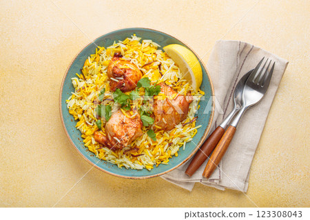 Traditional Indian dish chicken biryani with cilantro and lemon in a bowl top view on beige background 123308043