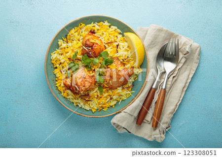 Traditional Indian dish chicken biryani with cilantro and lemon in a bowl top view on blue background 123308051