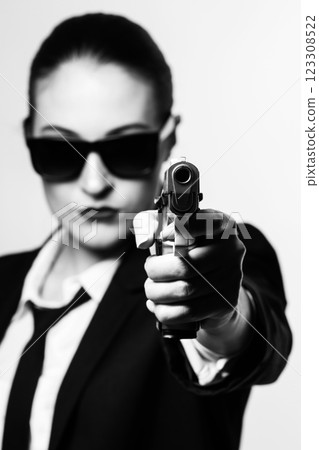 Woman with sunglasses and classic black suit pointing gun to camera Woman with sunglasses and classic black suit pointing gun to camera 123308522