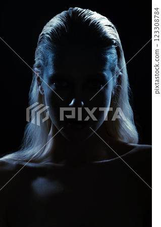 Studio portrait of woman silhouette partly illuminated with blue light Studio portrait of woman silhouette partly illuminated with blue light 123308784