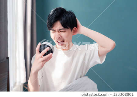 A young man who is anxious after oversleeping A young man who is anxious after oversleeping 123308801