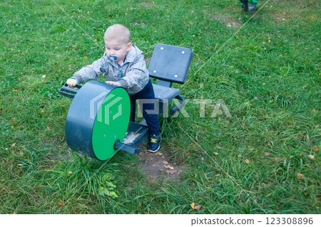 Toddler interacting with playground equipment. He is learning, developing coordination, and having fun in a natural setting. 123308896