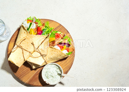 Greek chicken gyros wrap with vegetables and tzatziki sauce Greek chicken gyros wrap with vegetables and tzatziki sauce 123308924