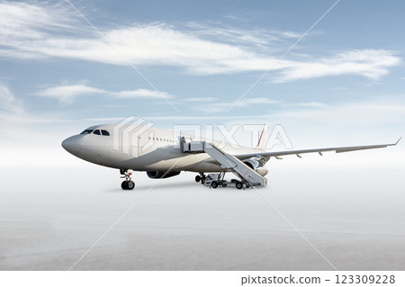 Wide body passenger aircraft with boarding air stairs on bright background with sky 123309228