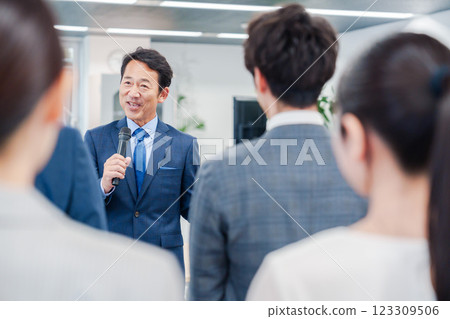 A male manager giving a speech at a morning meeting in the office A male manager giving a speech at a morning meeting in the office 123309506