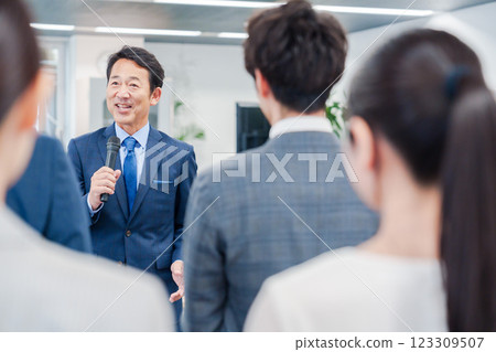 A male manager giving a speech at a morning meeting in the office A male manager giving a speech at a morning meeting in the office 123309507