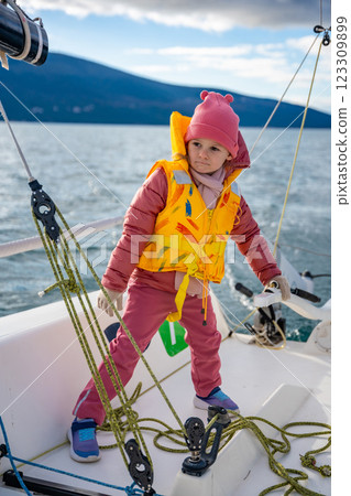Little girl learning to sail a yacht during training in the Kotor Bay, Montenegro, representing adventure, freedom, and nautical sport. Little girl learning to sail a yacht during training in the Kotor Bay, Montenegro, representing adventure, freedom, and nautical sport. 123309899