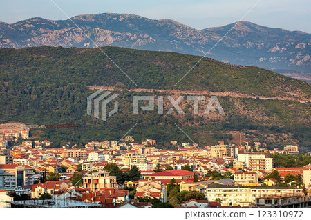 A breathtaking view of the bustling city of Budva set against a backdrop of lush mountains at sunset. A breathtaking view of the bustling city of Budva set against a backdrop of lush mountains at sunset. 123310972