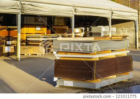 Wooden plywood sheets and timber stacked from floor to ceiling at lumber yard, large warehouse tent 123311775
