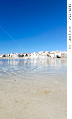 A picturesque coastal town with whitewashed buildings reflects on the calm waters of a lagoon A picturesque coastal town with whitewashed buildings reflects on the calm waters of a lagoon 123314843