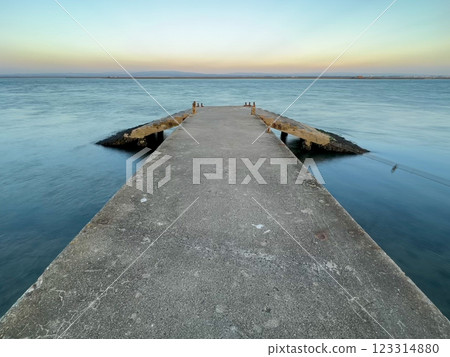 Concrete pier with dramatic sky and calm water Concrete pier with dramatic sky and calm water 123314880