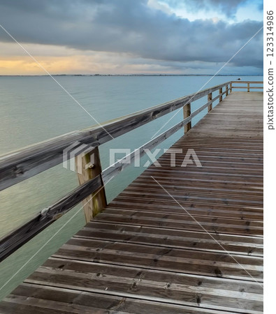 Empty wooden pier with dramatic sky and calm water 123314986