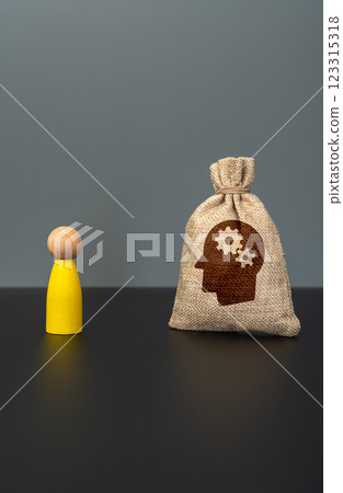 A bag of skills and intellectual abilities and a yellow human figurine. Concept of talent development, personal growth, knowledge acquisition, professional competence, and career potential. A bag of skills and intellectual abilities and a yellow human figurine. Concept of talent development, personal growth, knowledge acquisition, professional competence, and career potential. 123315318