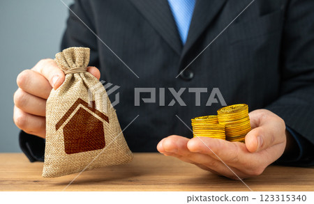 Businessman holding a bag with a house symbol and money coins. Sale of building permits. Housing stock, fees and payments for maintenance and repairs. 123315340