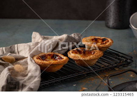 Golden-brown Portuguese custard tarts cooling on a wire rack Golden-brown Portuguese custard tarts cooling on a wire rack 123315465