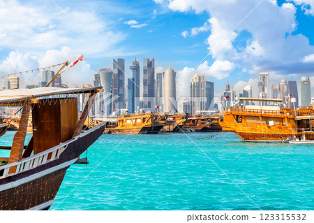 Traditional arab dhow fishermen boats anchored at pier with Doha modern business downtown center skyscrapers, Qatar 123315532