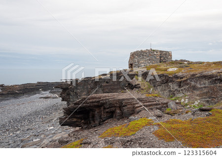 Old abandoned stone pillbox on a rocky seashore Old abandoned stone pillbox on a rocky seashore 123315604