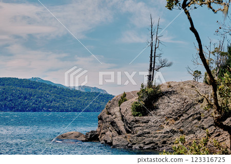 A huge boulder on the shore of a blue lake. 123316725
