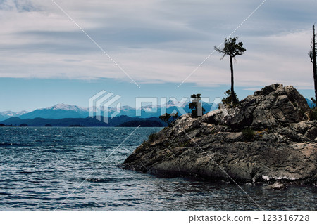 A huge boulder on the shore of a blue lake. A huge boulder on the shore of a blue lake. 123316728