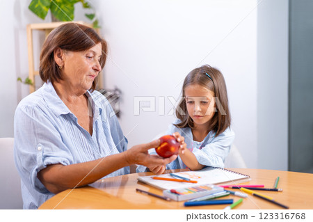 Grandmother placing apple on girl's hand over 123316768