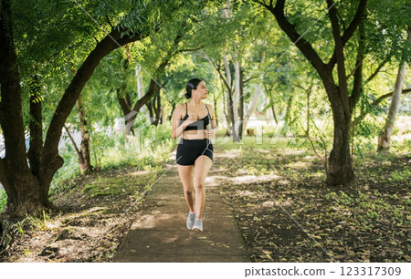 Healthy lifestyle concept of a woman jogging in a green park, Sporty young woman running in a park. Girl running in a park while listening to music, Lifestyle of sporty woman running in a park Healthy lifestyle concept of a woman jogging in a green park, Sporty young woman running in a park. Girl running in a park while listening to music, Lifestyle of sporty woman running in a park 123317309