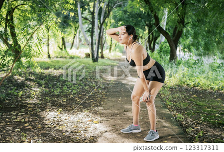A sporty girl taking a break after running. Concept of sporty girl tired and taking a break after running, Sporty young woman tired from running 123317311
