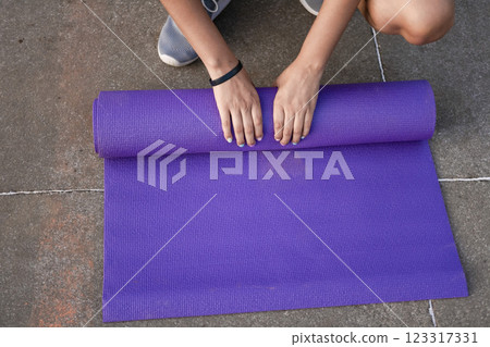 Woman hands rolling up the mat outside. Athlete woman's hands rolling up the mat after exercising. Concept of rolling up mat after exercise Woman hands rolling up the mat outside. Athlete woman's hands rolling up the mat after exercising. Concept of rolling up mat after exercise 123317331