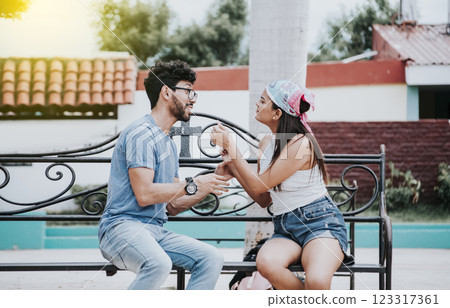 Young couple arguing sitting on a park bench, Concept of aggressive couples in the park. Upset couple arguing on a park bench. Man arguing with his girlfriend sitting in a park Young couple arguing sitting on a park bench, Concept of aggressive couples in the park. Upset couple arguing on a park bench. Man arguing with his girlfriend sitting in a park 123317361