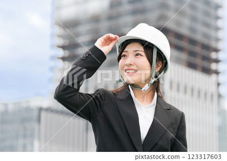A young woman in a suit and helmet standing at a construction site, construction manager, site supervisor, female civil engineer (Dobojo) A young woman in a suit and helmet standing at a construction site, construction manager, site supervisor, female civil engineer (Dobojo) 123317603