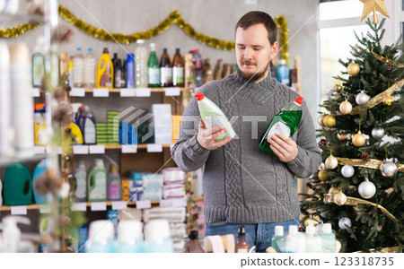Middle-aged guy choosing dishwashing liquid in store with New Year decoration 123318735