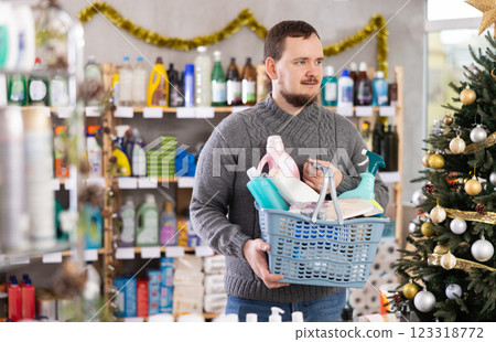 Man buyer with filled basket household chemistry wanders around store 123318772