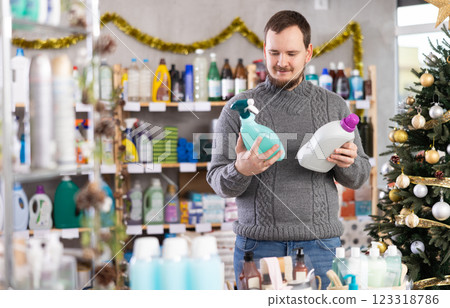 On New Year Eve, man choose and buy liquid washing powder and tile cleaner spray On New Year Eve, man choose and buy liquid washing powder and tile cleaner spray 123318786