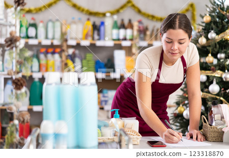 Young woman restocking using paper in store with New Year decoration 123318870